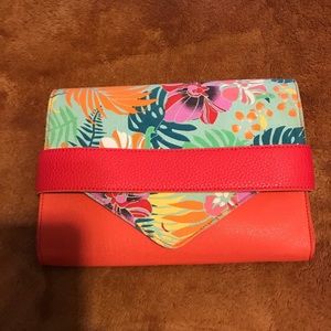 Never used clutch. Bright orange, Flower flap and tuck closer. Multi pockets.